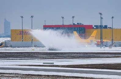 Eine Schneefräse räumt Schnee von einer Landebahn vor dem DHL-Hub auf dem Flughafen Leipzig/Halle.