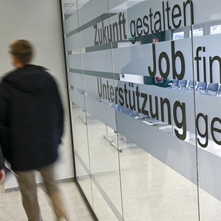 Menschen gehen in den Gängen einer Agentur für Arbeit.