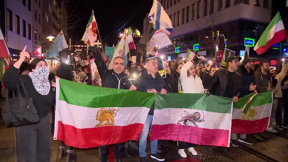 Menschen demonstrieren mit Fahnen auf einer Straße in Hannover.