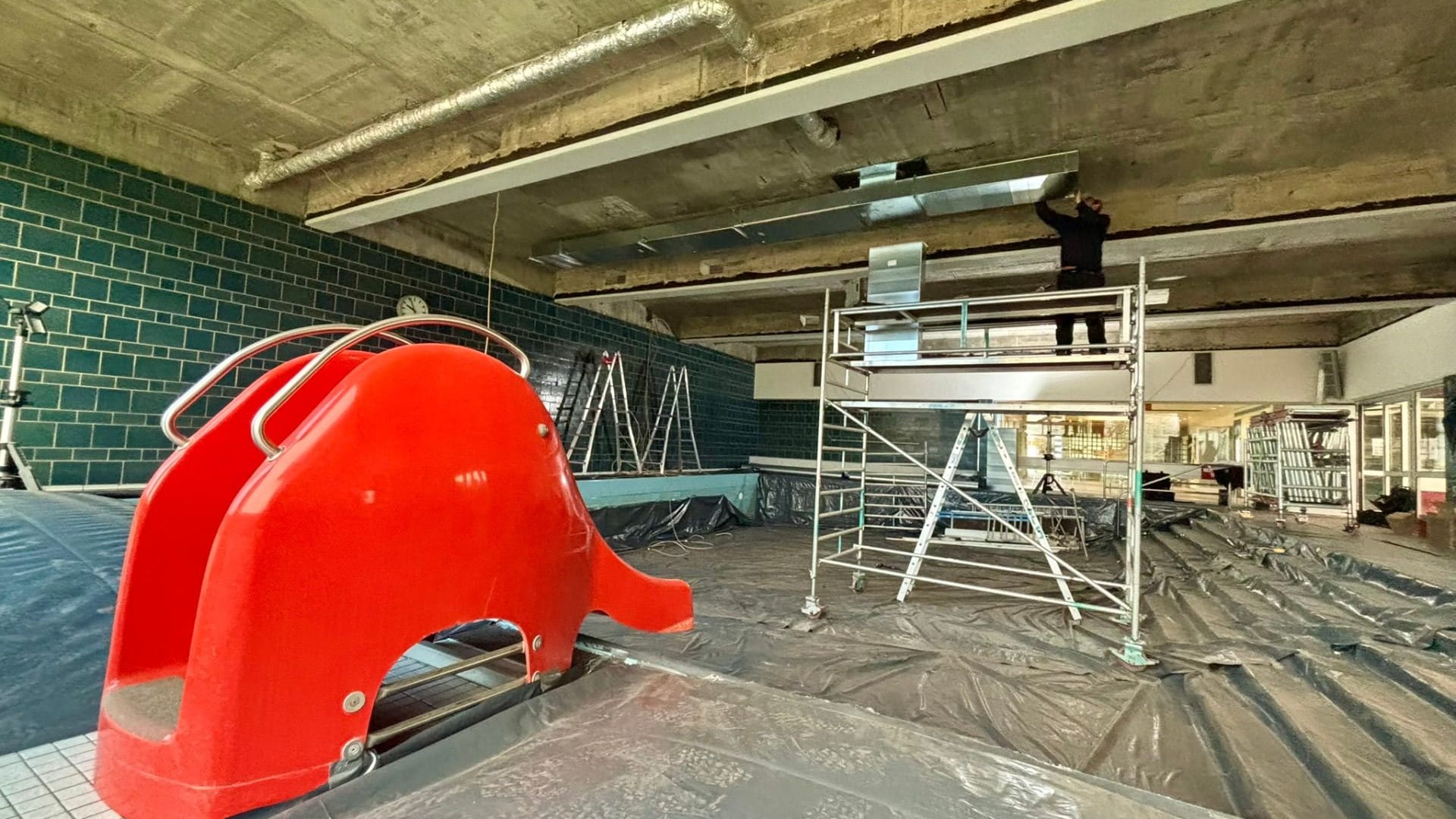 Arbeiter reparieren Decke der Schwimmhalle: Sicherungsmaßnahmen ermöglichen Wiedereröffnung.