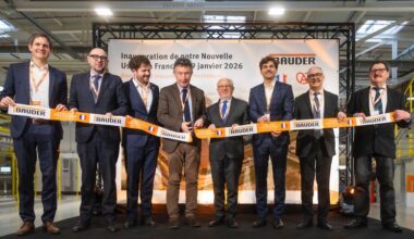 Eine Gruppe von acht Personen steht auf einer Bühne und hält ein Band bei einer Eröffnungszeremonie.