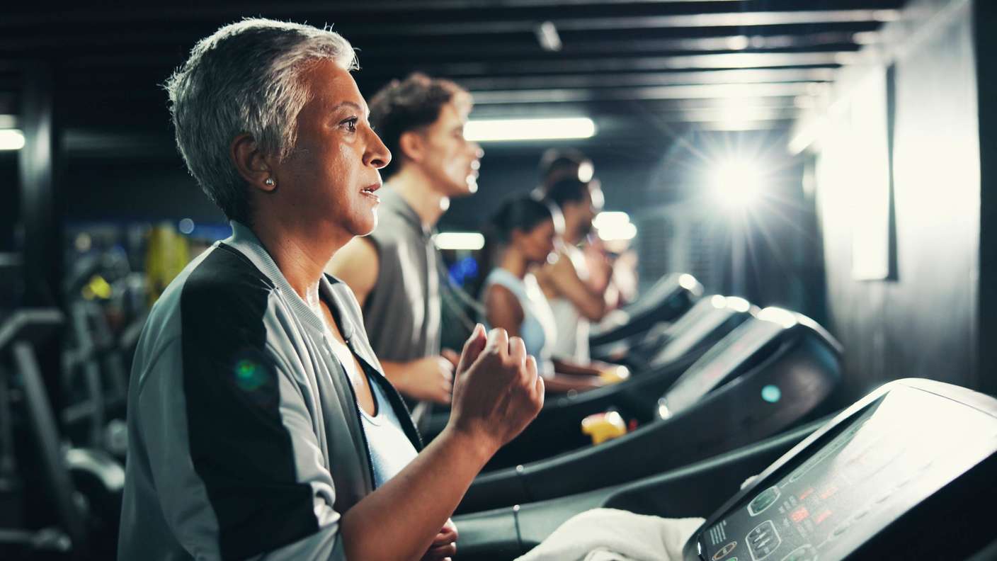 Ältere Frau trainiert im Cardio-Bereich des Fitnessstudios auf dem Laufband.