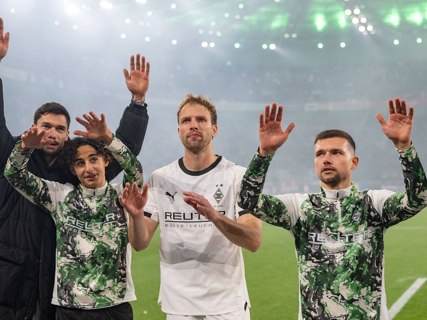 Die Spieler von Borussia Mönchengladbach bedanken sich bei den Fans und reißen die Arme nach oben.