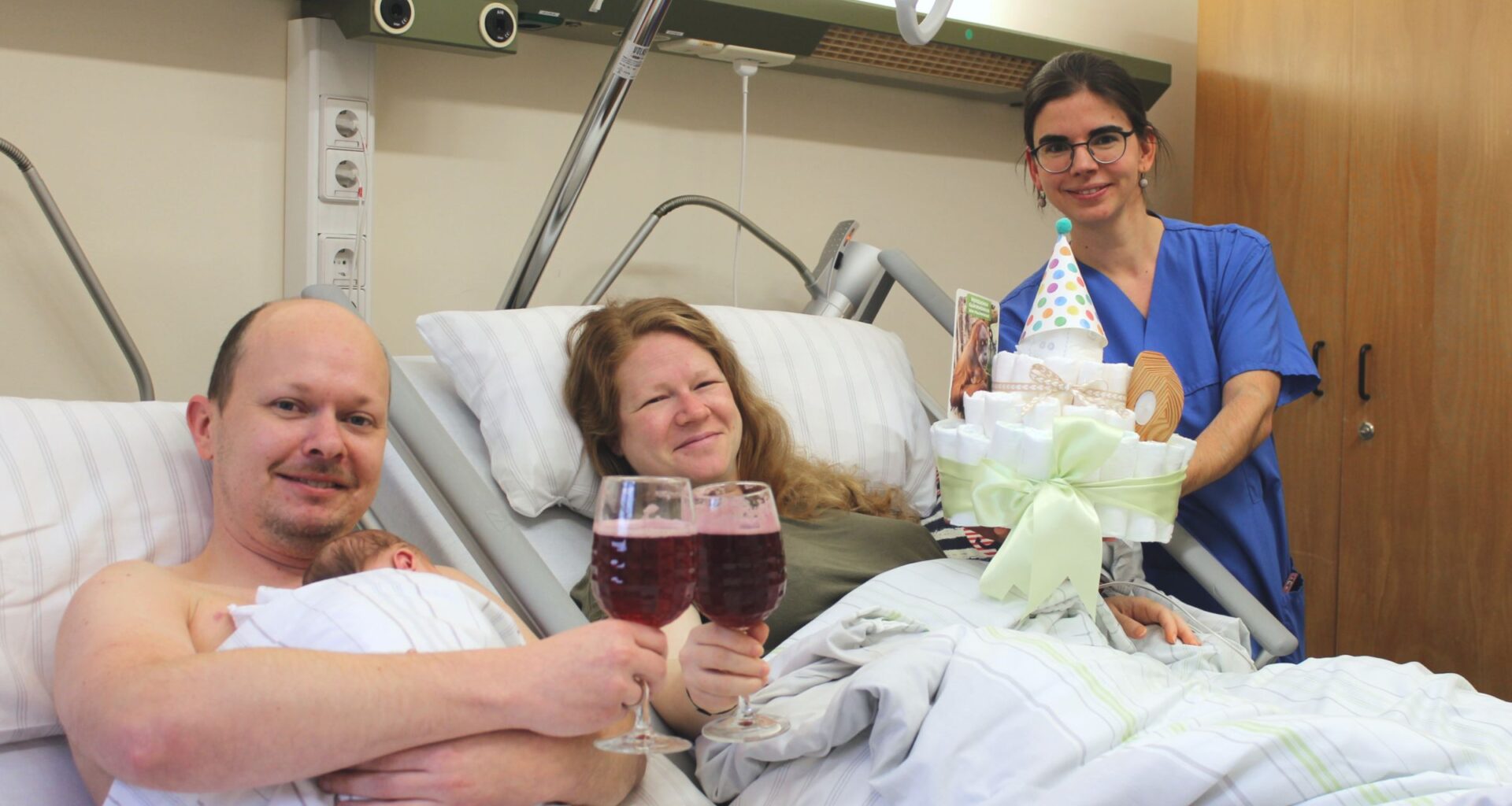 Die Leitende Hebamme Lisa Mühlberg gratuliert den frischgebackenen Eltern mit Brause und einer Windeltorte. Foto: Diako/Victor Franke