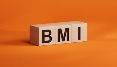 Würfel bilden den Ausdruck BMI (Body Mass Index), der auf orangefarbenem Hintergrund dargestellt wird.