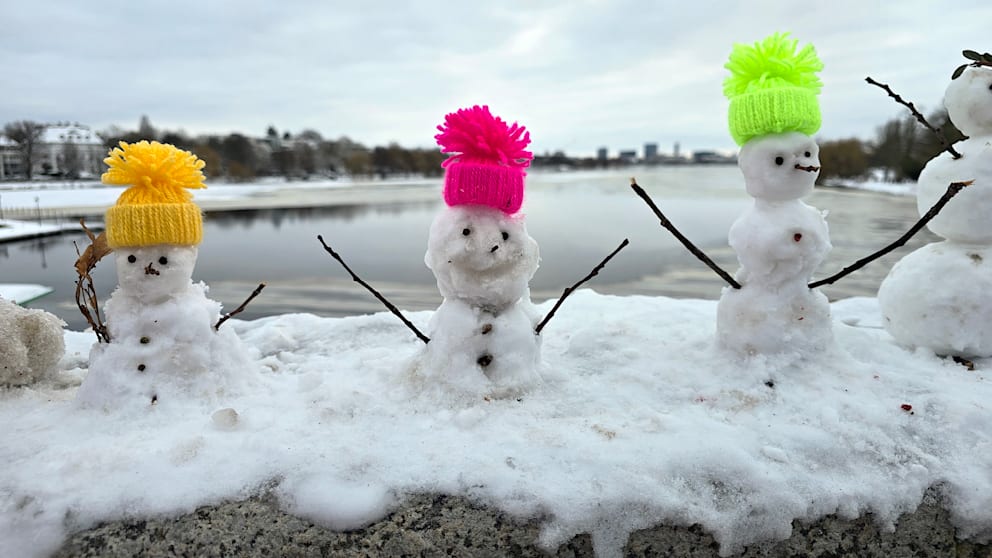 Die Schneemänner tragen farbenfrohe Strickmützen