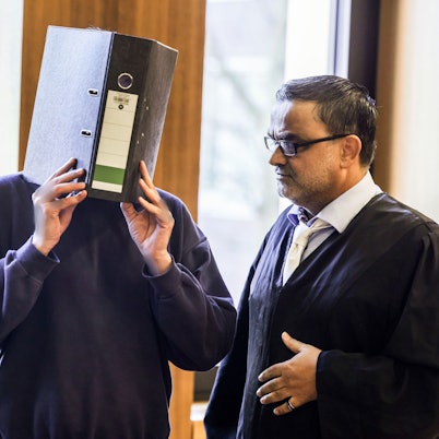 Der Angeklagte Krankenpfleger (M) steht mit einem Aktenordner vor dem Gesicht neben seinem Anwalt Volker Breyer (r) im Gerichtssaal. Das Aachener Landgericht hat Ulrich S. vor einem Monat wegen des Mordes an zehn Patienten zu einer lebenslangen Freiheitsstrafe verurteilt.