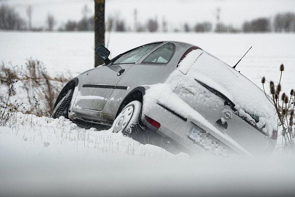 Fuß vom Gas: Ein Auto liegt an einer schneebedeckten Landstraße im Graben. - © dpa