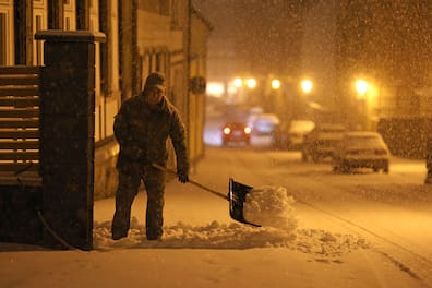 Ein Anwohner in Wernigerode räumt mit einer Schneeschaufel den Weg frei. Heftiger Winterbruch sorgt für Verkehrsbehinderungen.