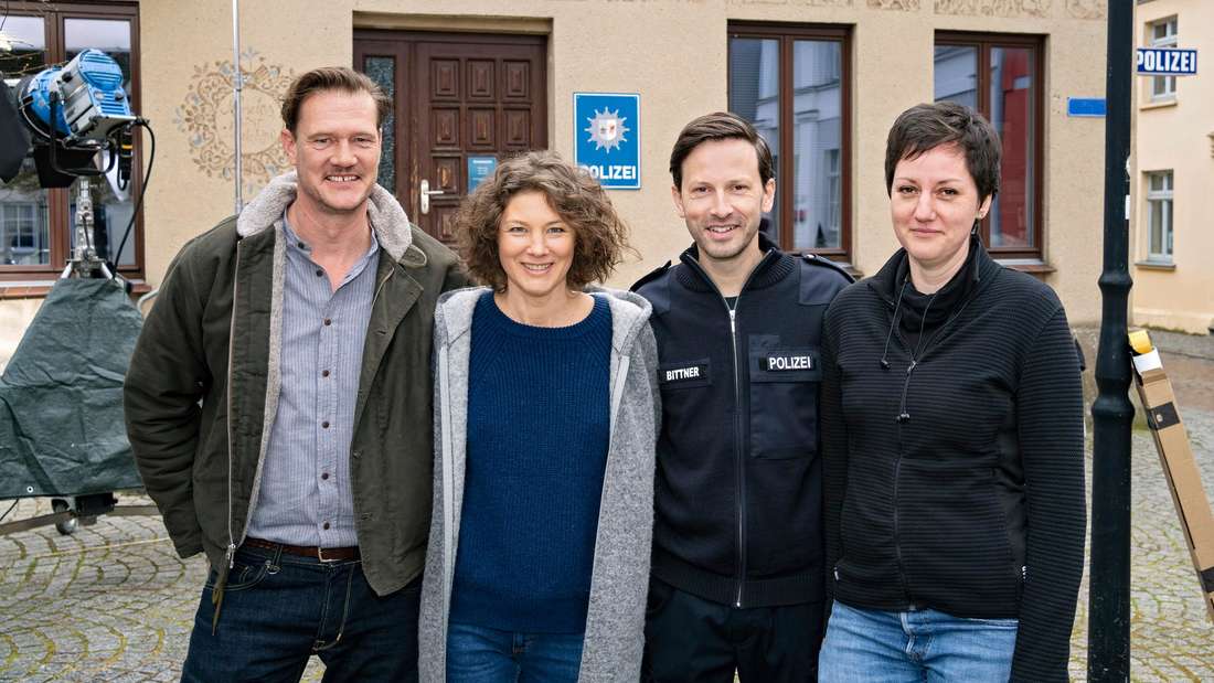 Vier Menschen stehen vor der Kamera.