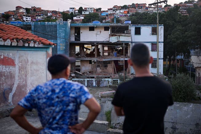 Anwohner blicken am 4. Januar 2026 in Catia La Mar nördlich von Caracas auf ein beschädigtes Wohngebäude.
