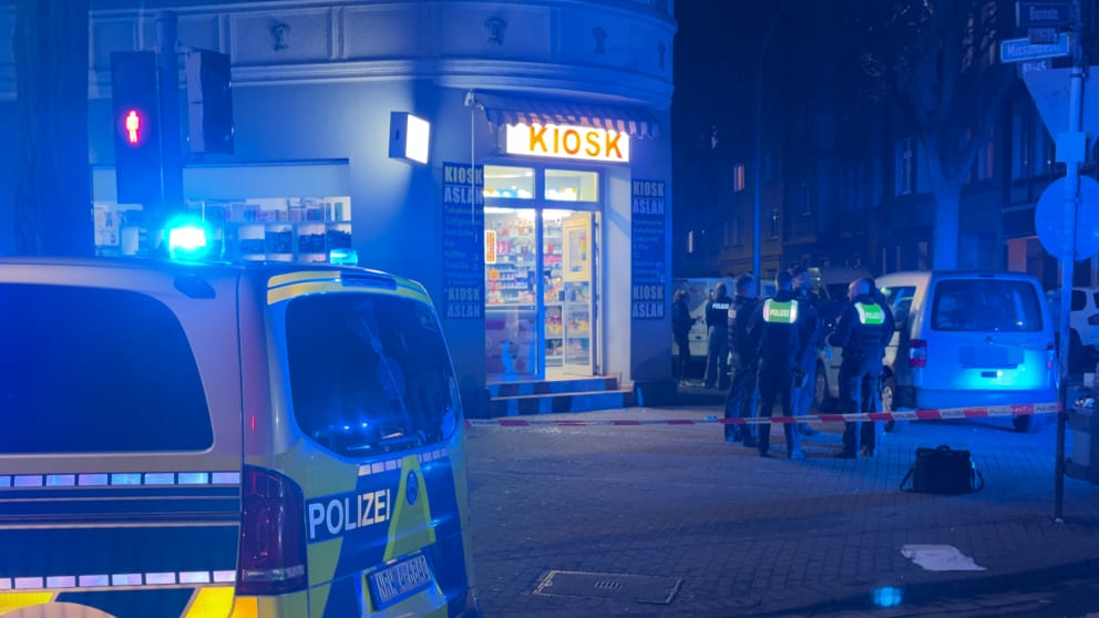 Polizisten besprechen sich im abgesperrten Tatortbereich vor dem Kiosk