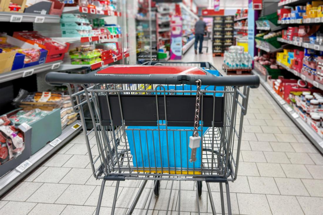 Bavaria, Germany - August 22, 2025: A shopping cart stands in an aisle of a food supermarket. Symbolic photo shopping, p 