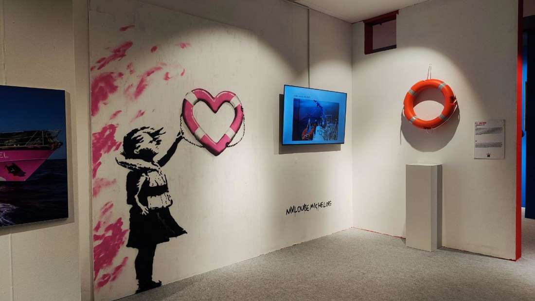 Blick auf eine Variante von Girl with Balloon mit einem Rettungsring und ein Bildschirm.