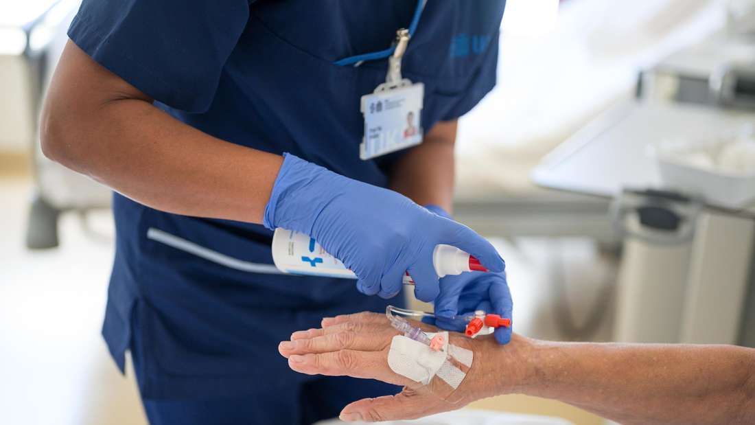 Eine Pflegekraft egt einer Patientin eine Infusion.