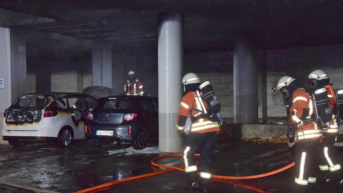 Am Berliner Platz brennen kurz nach Mitternacht zwei Fahrzeuge unter einem Vordach eines Hochhauses. 
