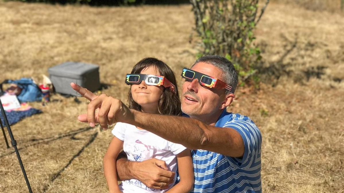 Am 12. August 2026 verdunkelt sich der Himmel über Teilen Europas. Auf einigen AIDA-Kreuzfahrten lässt sich dieses Naturphänomen besonders gut beobachten. Father and daughter looking at the sun during a solar eclipse on a country park, family outdoor activity