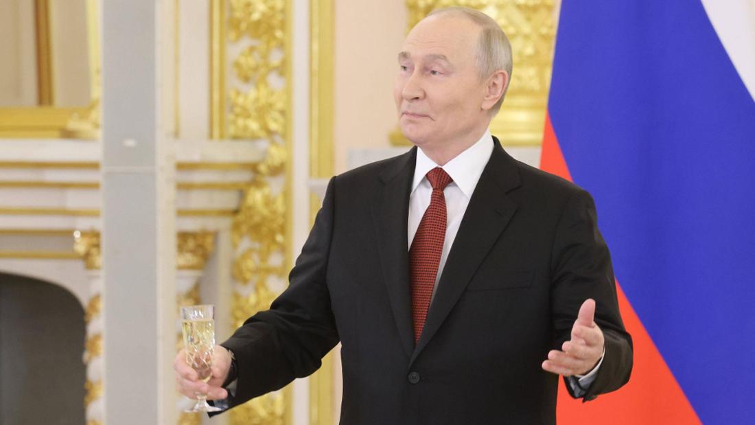 Wladimir Putin mit Glas in der Hand und einladender Geste