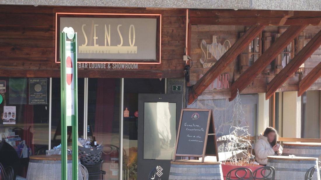 Frau sitzt seitlich vor Eingang von Bar