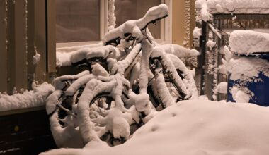 Eingeschneite Fahrräder stehen an einer Hauswand.