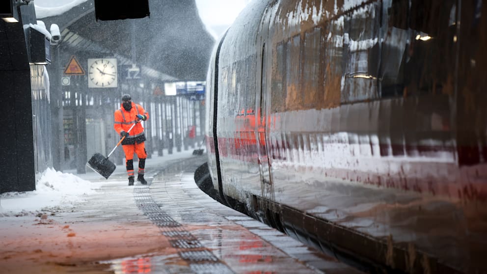 Mitarbeiter sind damit beschäftigt, die Bahnsteige von den Schneemassen zu befreien