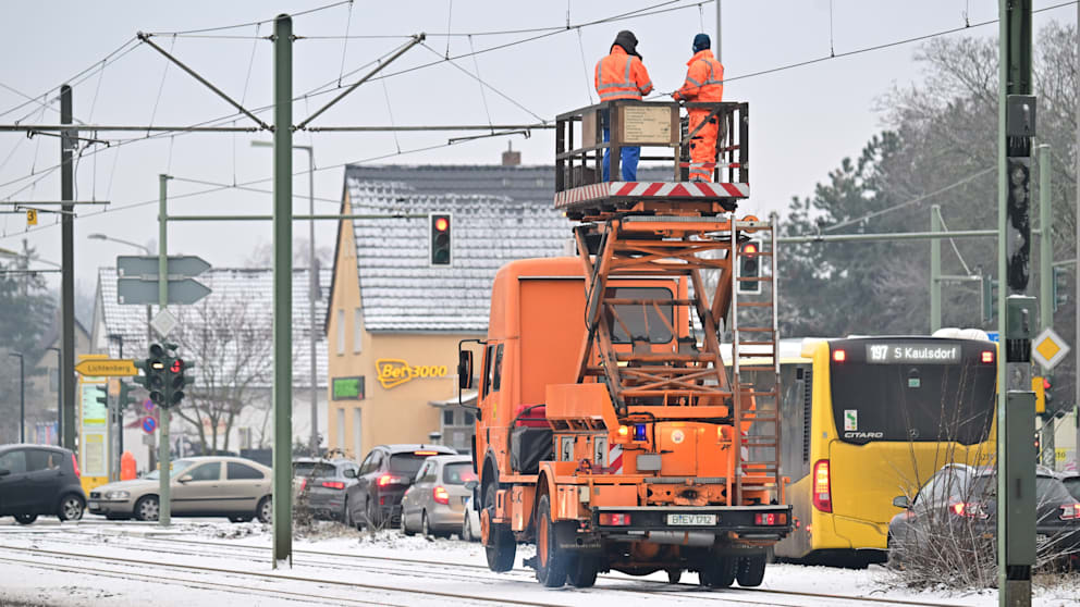 Arbeiter enteisen die Oberleitung einer Tram-Strecke