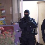 Zwei vermummte Polizisten stehen vor einem Hauseingang.