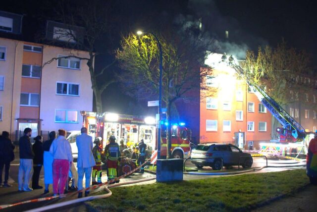 Menschen blicken auf einen Brandeinsatz der Feuerwehr.