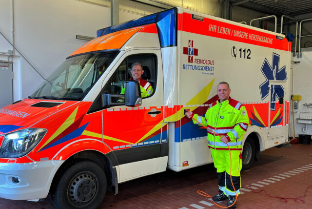 Zwei Sanitäter in und an einem Rettungsdienstfahrzeug der Firma Reinoldus.