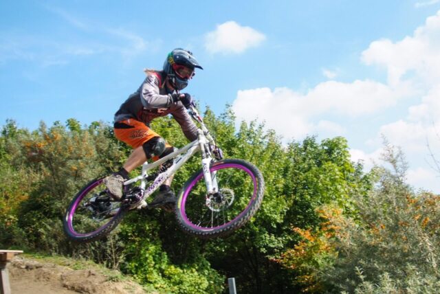 Ein Mountainbiker springt über einen Hügel.