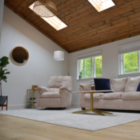 Ein Wohnzimmer mit hellen Möbeln und einem dunklen Kamin.