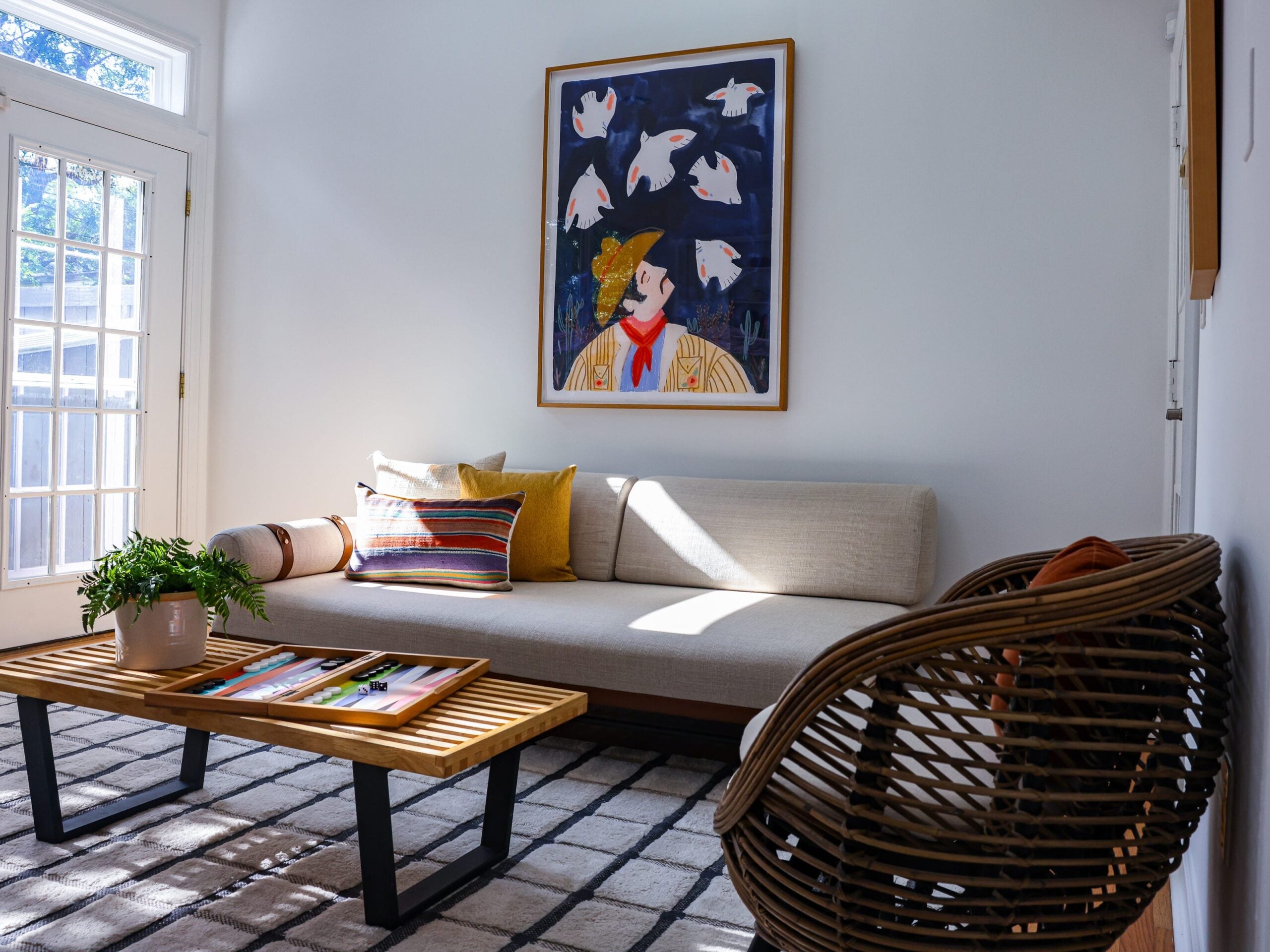 A living room decorated with an art piece of a man surrounded by birds.