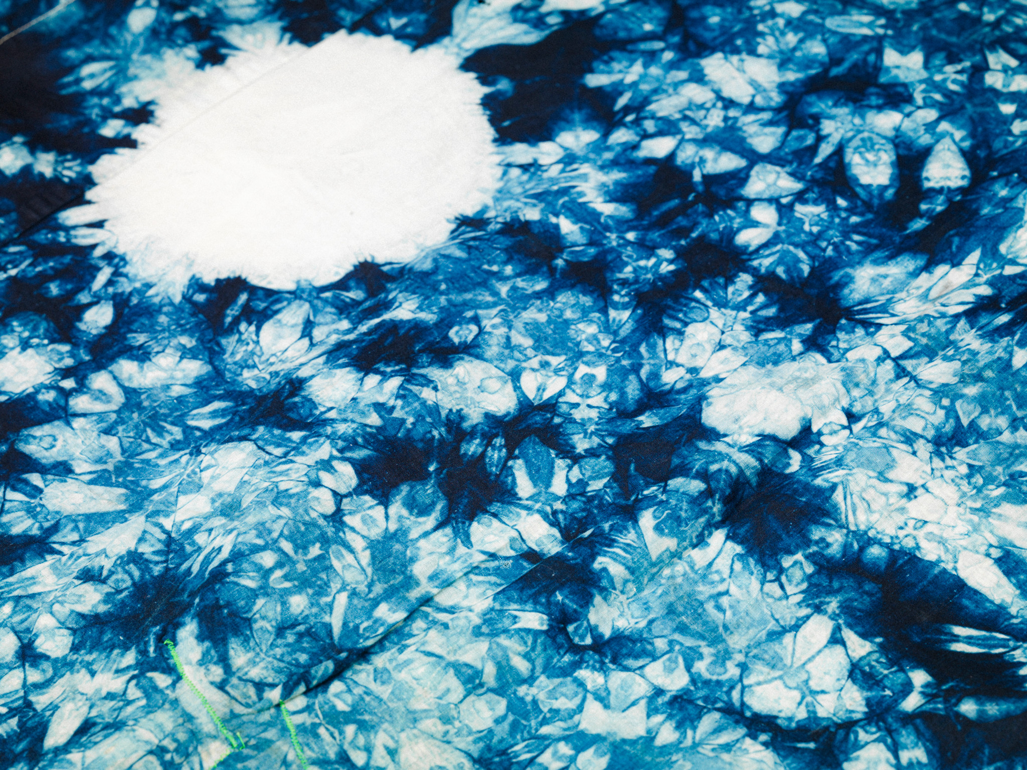 Nahaufnahme eines blauen Batikmusters mit weissen Kreisen und marmorierten Strukturen.