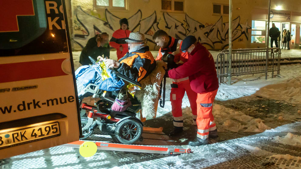 Ein Mann im Rollstuhl wird an der Notunterkunft von einem Krankentransporter abgeholt