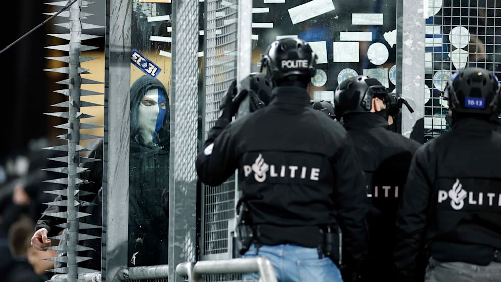 Ein Fan mit Maske versperrt der Polizei den Zugang zum Block