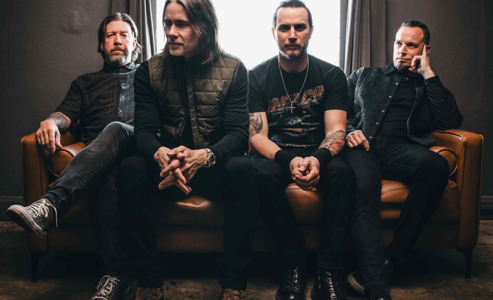 Die vier Mitglieder von Alter Bridge sitzen nebeneinander auf einem Sofa.