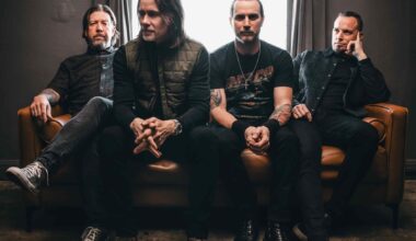 Die vier Mitglieder von Alter Bridge sitzen nebeneinander auf einem Sofa.