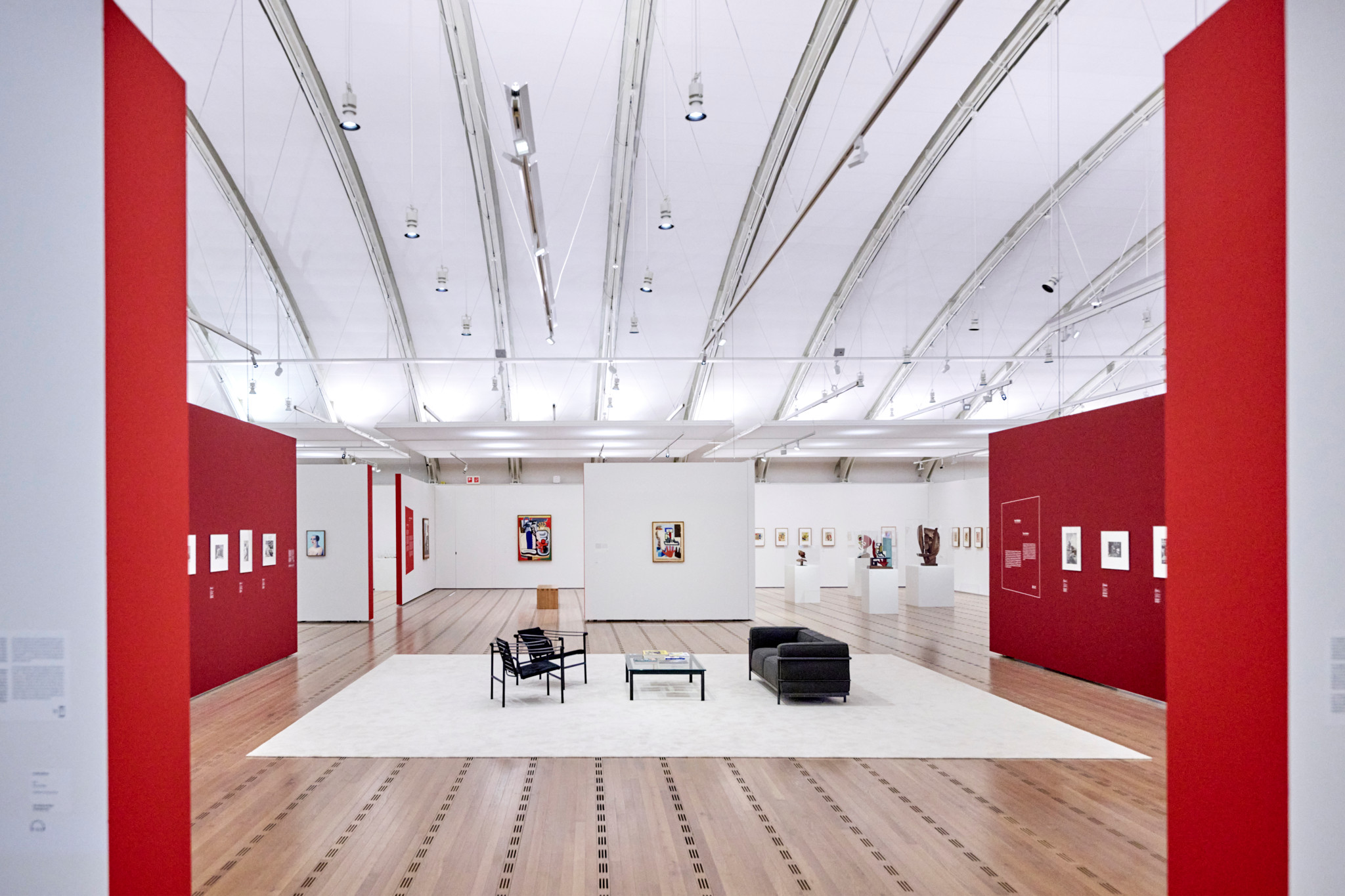 Innenansicht einer Ausstellung über Le Corbusier im Zentrum Paul Klee mit roten und weissen Wänden, Kunstwerken und Möbeln.