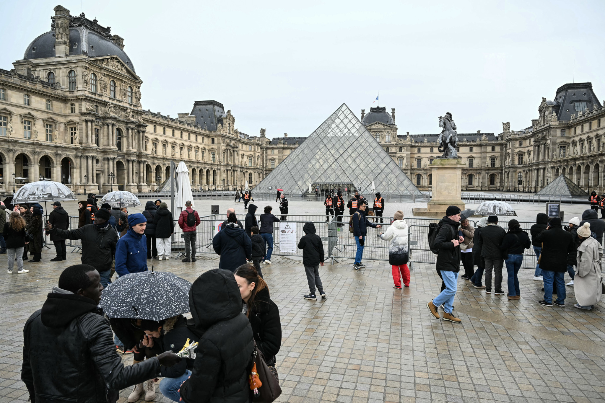 Touristen stehen vor Absperrungen rund um die Louvre-Pyramide in Paris, da das Museum wegen eines Streiks am 12. Januar 2026 geschlossen ist.