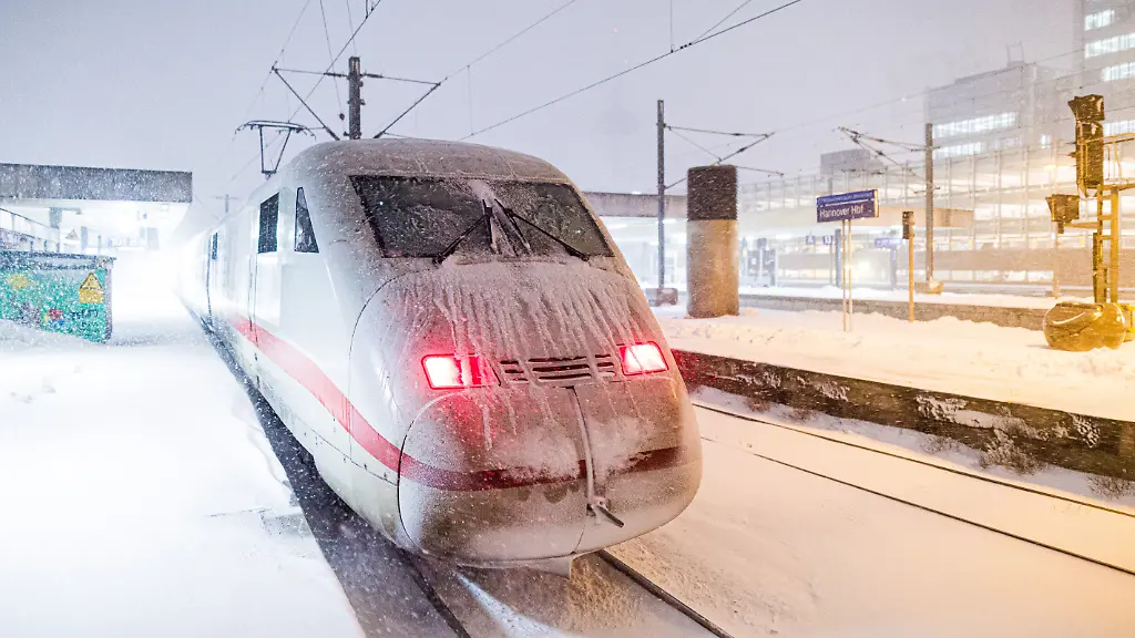 Ein-ICE-steht-am-fruehen-Morgen-an-einem-verschneiten-Gleis-im-Hauptbahnhof