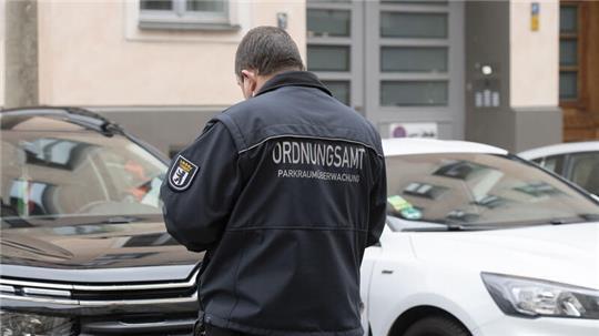 Ein Mitarbeiter eines Ordnungsamts kontrolliert ein Fahrzeug (Symbolbild).