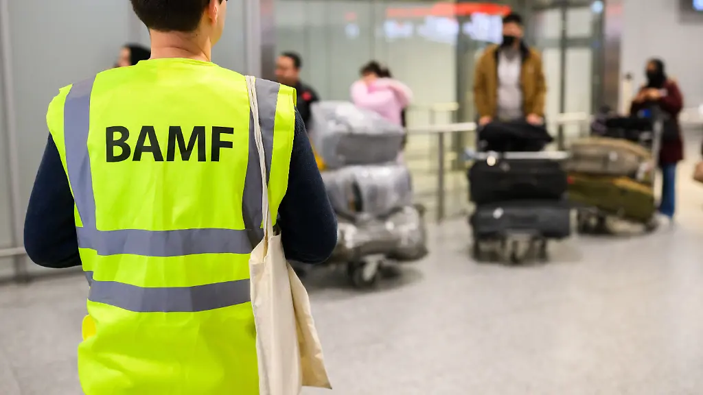 Ein-Mitarbeiter-vom-BAMF-Bundesamt-fuer-Migration-und-Fluechtlinge-steht-im-Flughafen-Hannover-vor-Afghaninnen-und-Afghanen-aus-den-Bundesaufnahmeprogrammen