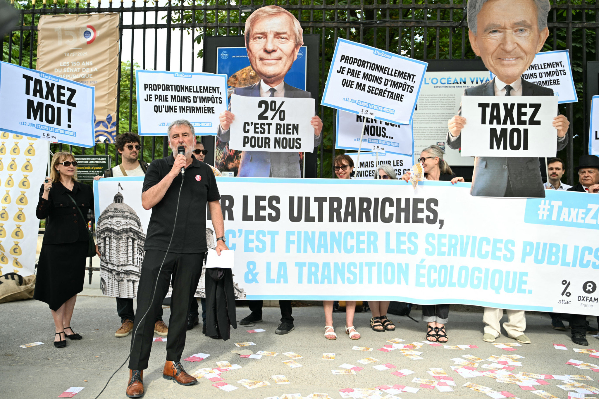 Vincent Drezet von Attac spricht vor Plakaten während einer Protestaktion vor dem Senat in Paris am 12. Juni 2025 über die Beschlussfassung einer Mindeststeuer für Ultrareiche.