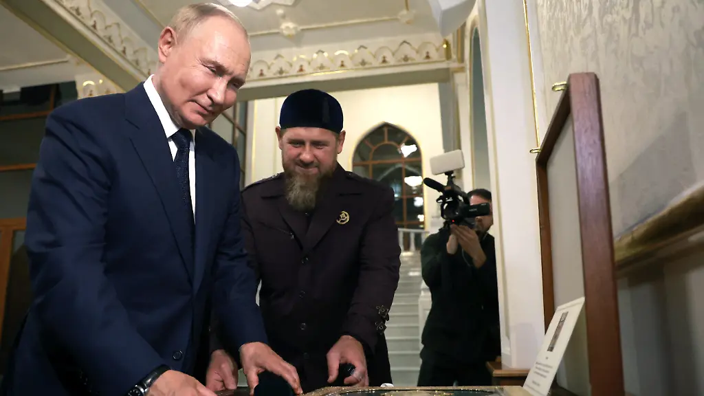 In-this-pool-photograph-distributed-by-Russian-state-owned-Sputnik-agency-head-of-the-Chechen-Republic-Ramzan-Kadyrov-C-shows-Koran-to-Russia-s-President-Vladimir-Putin-L-during-his-visit-to-Chechnya-in-Grozny-on-August-20-2024