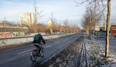 Radfahrer fährt auf Fahrbahn, der Radweg ist von Schneematsch bedeckt.