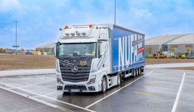 Ein wei&szlig;er Mercedes-Benz Sattelzug steht auf dem Au&szlig;engel&auml;nde der Messe Karlsruhe. Der blaue Auflieger tr&auml;gt die gro&szlig;fl&auml;chige Aufschrift &bdquo;NUFAM &ndash; Die Nutzfahrzeugmesse&ldquo;. Im Hintergrund sind Messehallen unter einem leicht bew&ouml;lkten Himmel zu sehen.