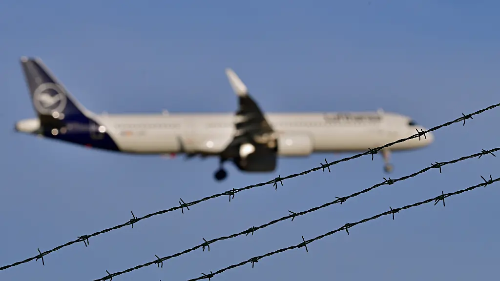 Symbolbild-Abschiebung-Flugzeug-fliegt-hinter-Stacheldraht