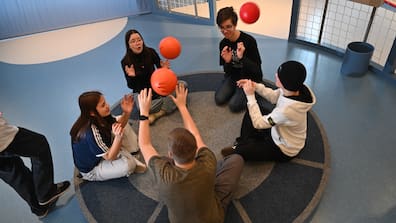 Schüler werfen sich Bälle auf einer Drehscheibe zu. 