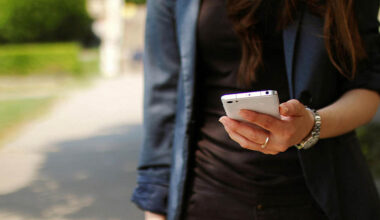 Bildbeschreibung: Eine Frau die ein Handy in der Hand hält.