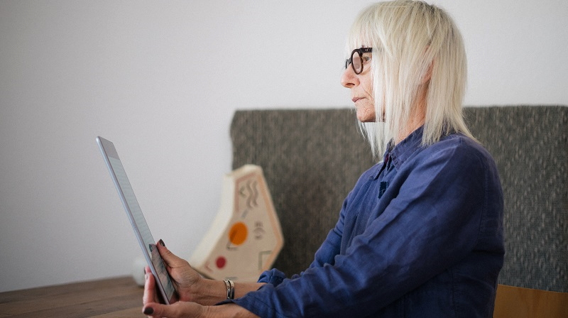 Bildbeschreibung: Eine ältere Frau an einem Tablet.